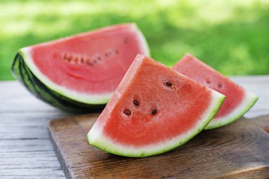 Dışarıdaki ahşap masa arkasında taze dilimlenmiş karpuz.