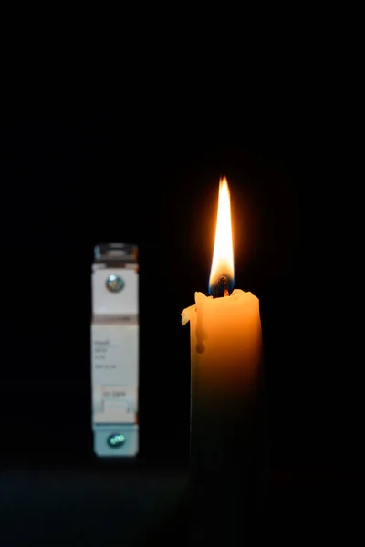 家庭の停電時には 電気メーターの近くの暗闇の中で手にキャンドルが輝きます 電気のない国の都市 — ストック写真