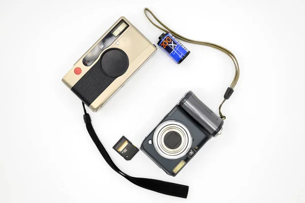 白い背景にフィルムとメモリカードとコンパクトな黒いデジタルとチタンフィルムカメラのクローズアップ — ストック写真