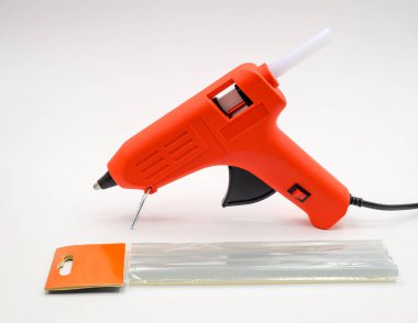 red glue gun with silicone sticks on a white background. Close-up. Side view