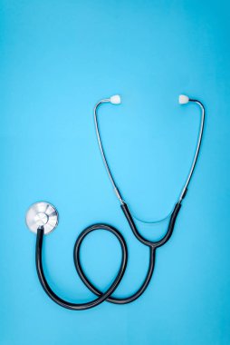 Mavi arka planda steteskop. Kardiyoloji konsepti, üst görünüm, dikey