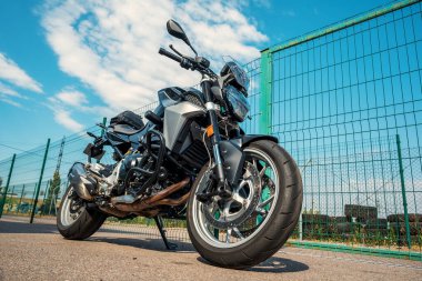 Parlak güneşli bir günde, çitin yakınına park etmiş motosiklet yarışı.