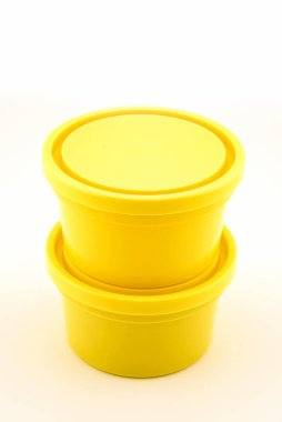 Yiyecek depolamak için kapağı olan iki sarı plastik kap, beyaz arka planda yakın plan görüntüsü.