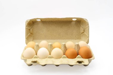 Beyaz arka planda on tane kahverengi yumurta ve kırpma kutusu var. Yumurta kabında taze kırsal tavuk yumurtaları, beyaz arka planda üst görüntüyü kapatın.