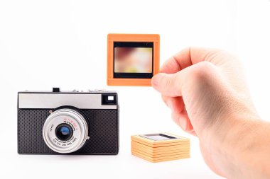 Retro film kamerası 35 mm, bir adam elinde bir fotoğraf slaydı tutuyor, beyaz arka planda, yakın plan.