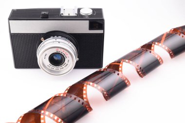 Retro kompakt film kamerası ve negatif pozlanmış fotografik film beyaz arkaplanda izole edilmiş, yakın plan