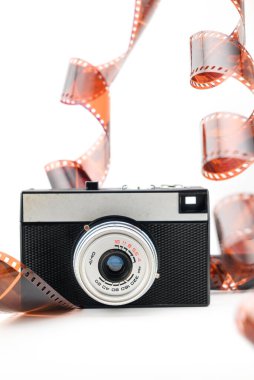 Retro kompakt film kamerası ve negatif pozlanmış fotografik film beyaz arkaplanda izole edilmiş, yakın plan