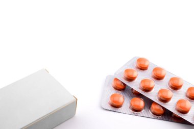 Gri karton kutu ve turuncu tıbbi haplar. Kabarcık paketinde. Yakın plan beyaz, yan görüş.