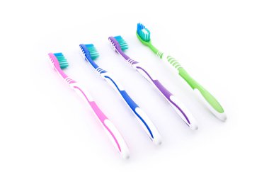 Renkli diş fırçaları beyaz arkaplanda düzgün bir şekilde dizilmiş, her diş fırçasının günlük diş bakımına uygun eşsiz bir rengi ve tasarımı var, yakın plan, yan görünüm