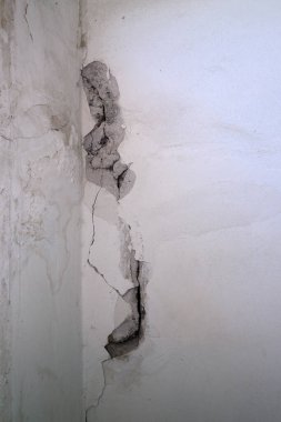 Eski bir binanın duvarında çatlak, çökmüş alçı, harap olmuş bir binanın beton duvarı.