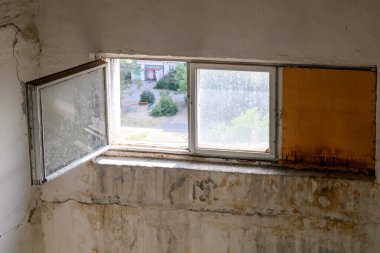 Terk edilmiş eski binada kirli bir duvar. Açık ahşap penceresi ve beton duvarında çatlaklar var. Acil durum eski konut binası.