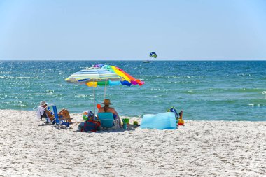 GULF SHORES, AL / USA - 3 Mayıs 2023: İnsanlar Meksika Körfezi 'ndeki Gulf Shores Plajı' nda güneşli güzel bir günün tadını çıkarıyorlar.     