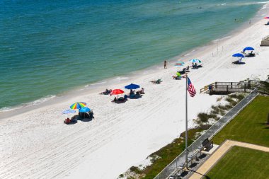 GULF SHORES, AL / USA - 3 Mayıs 2023: İnsanlar Meksika Körfezi 'ndeki Gulf Shores Plajı' nda güneşli güzel bir günün tadını çıkarıyorlar.     