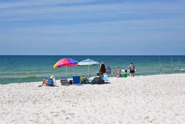 GULF SHORES, AL / USA - 3 Mayıs 2023: İnsanlar Meksika Körfezi 'ndeki Gulf Shores Plajı' nda güneşli güzel bir günün tadını çıkarıyorlar.     