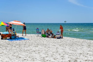 GULF SHORES, AL / USA - 3 Mayıs 2023: İnsanlar Meksika Körfezi 'ndeki Gulf Shores Plajı' nda güneşli güzel bir günün tadını çıkarıyorlar.     