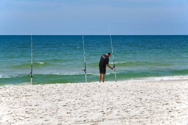GULF SHORES, AL / USA - 3 Mayıs 2023: Genç adam Meksika Körfezi 'ndeki Körfez Kıyısı Sahili' nde güneşli bir günün tadını çıkarırken     