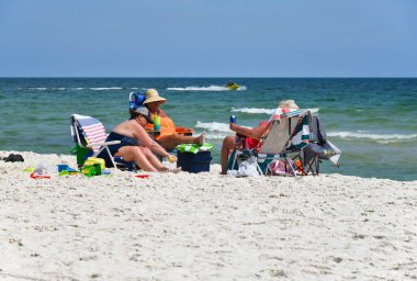 GULF SHORES, AL / USA - 4 Mayıs 2023: İnsanlar Meksika Körfezi 'ndeki Gulf Shores Beach' te güneşli güzel bir günün tadını çıkarıyorlar