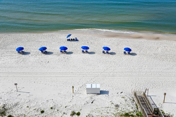 海湾海岸白色沙滩上有雨伞的蓝色海滩椅子 图库图片