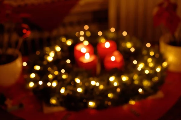 Christmas Wreath with Fairy Lights and burning Advent Candles Blurred Background