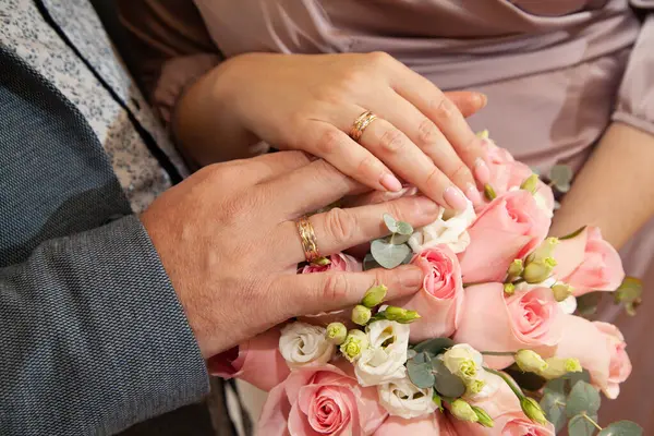 新婚夫妇手里拿着结婚戒指 后面是一束鲜花 — 图库照片#