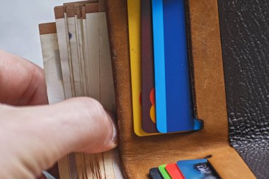 Gri arka planda bir yığın kitap ve kredi kartı olan siyah deri cüzdan.