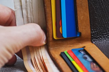 Gri bir geçmişi olan bir cüzdan. Tasarruf konsepti. Gri arka planda bir yığın kitap ve kredi kartı olan siyah deri cüzdan.