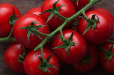 Ahşap zemin üzerinde bir dalda kiraz domatesleri, yakın plan. Ahşap zemin üzerinde taze vişneli domatesler..