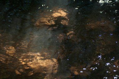 Geceleri ormanda akan su gibi. Soyut arkaplan ve doku. Nehirdeki suyun yüzeyine yansıyan güneş ışığı..