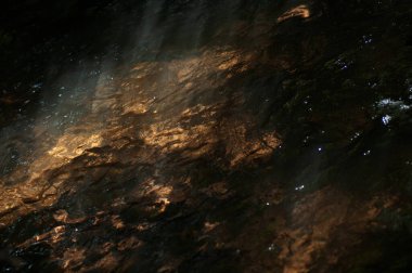 Güneş ışınları ve yüzeyde yansımaları olan soyut karanlık su yüzeyi. Karanlık ve doğal arka planda güneş ışığının su yüzeyine yansıması..