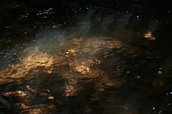 表面に太陽光と反射を持つ抽象的な暗い水面暗い自然背景の水面に太陽光が反射する — ストック写真