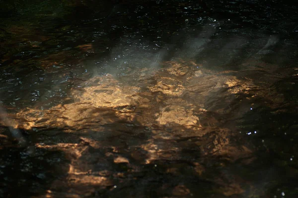 Abstrakte Dunkle Wasseroberfläche Mit Sonnenstrahlen Und Reflexionen Auf Der Oberfläche — Stockfoto