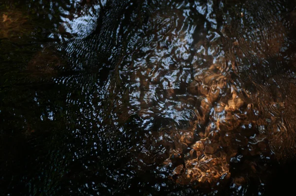 Abstrakte Dunkle Wasseroberfläche Mit Sonnenstrahlen Und Reflexionen Auf Der Oberfläche — Stockfoto
