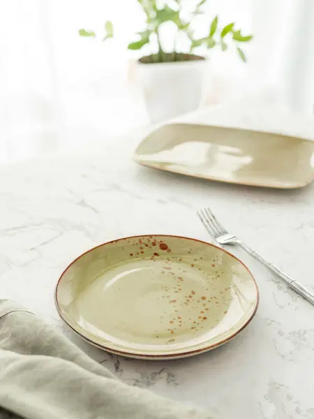 空白的绿色餐盘 桌布铺在白色大理石桌子上 白桌上有叉子的绿色陶瓷盘 图库图片