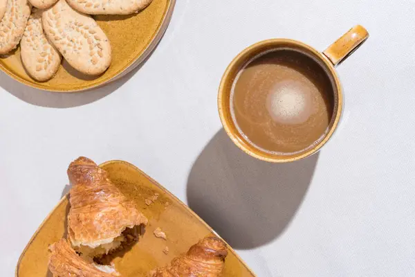 在瓷盘上的片状羊角面包旁边 放着一杯咖啡 背景质感很好 平铺咖啡饮料 图库图片
