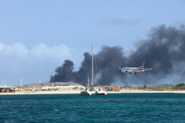 ORANJESTAD, ARUBA - 07 Nisan 2022: Karayip adası Aruba 'daki Oranjestad yakınlarındaki Serlimar atık sahasında çöp yakılırken Queen Beatrix Havaalanına inen uçak