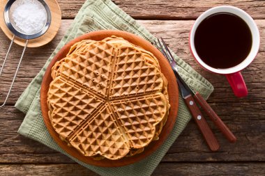 Taze ev yapımı kalp şeklinde waffle yığınları bir fincan çay ve yanında pudra şekeri ile ahşap üzerinde fotoğraflanmış (Seçici Odak, üst waffle üzerine odaklan)