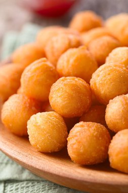Fresh round baked Duchess potatoes or croquettes on wooden plate, ketchup in the back (Very shallow depth of field, Focus one third into the potato balls)