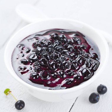 Fresh homemade jam made of Patagonian Calafate berries (lat. Berberis heterophylla), served in white bowl (Selective Focus, Focus one third into the jam)