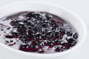 Fresh homemade jam made of Patagonian Calafate berries (lat. Berberis heterophylla), served in white bowl (Selective Focus, Focus one third into the jam)