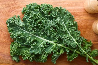 Fresh raw curly kale or leaf cabbage (lat. Brassica oleracea) photographed overhead on wood