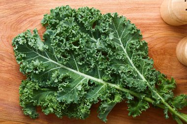 Fresh raw curly kale or leaf cabbage (lat. Brassica oleracea) photographed overhead on wood clipart