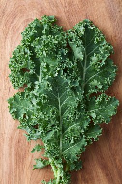 Fresh raw curly kale or leaf cabbage (lat. Brassica oleracea) photographed overhead on wood (Selective Focus)