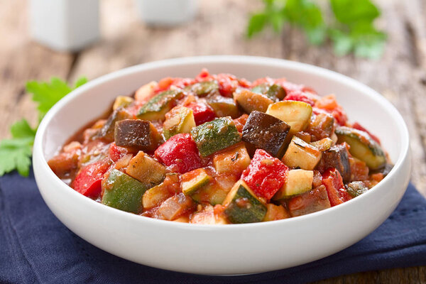 Fresh Ratatouille, a traditional French vegan vegetable stew made of eggplants, zucchini, bell pepper, tomato and onion with herbs (Selective Focus, Focus in the middle of the image)