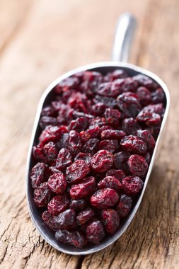 Dried Cranberries in metal scoop on wood (Selective Focus, Focus one third into the image) clipart