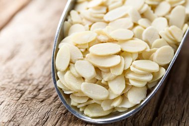 Tahta masadaki metal kepçeyle kurutulmuş bademler (Seçici Odaklanma, görüntünün ortasına odaklan)