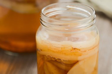 Ev yapımı siyah çay kombu çayı ya da bir sürü scoby 'li cam kavanozda çay mantarı, sağlıklı bir mayalanmış probiyotik içecek (Seçici Odak, üst scoby' nin ön tarafına odaklan)