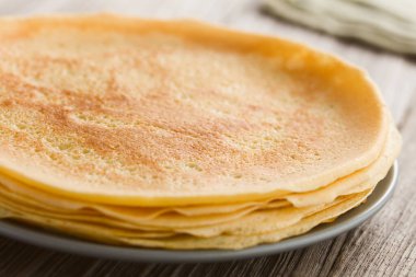 Bir yığın taze ev yapımı krep, ince Fransız usulü krep, arkasında un ve yumurta olan tabakta (Seçici Odaklanma, üçte birini kreplere odakla)