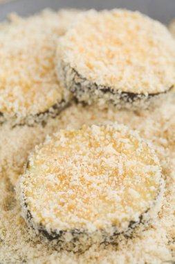 Ekmek kırıntılarıyla kaplı bir tabakta çiğ ekmeklenmiş patlıcan ya da patlıcan dilimleri (Seçici Odaklanma, patlıcan diliminin ortasına odaklan)