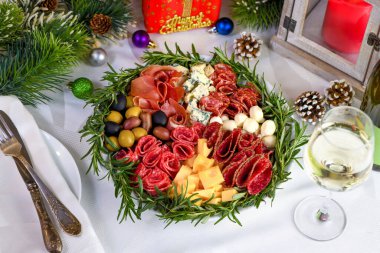 Delicacy assorted appetizer platter of salami and cheese, Parma ham, olives. An original antipasto serving for a Christmas party. clipart