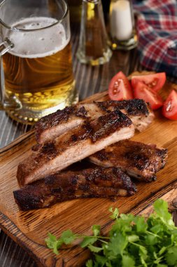 Ahşap tabakta barbekü soslu leziz ızgara domuz eti, otlar ve sebzeler.